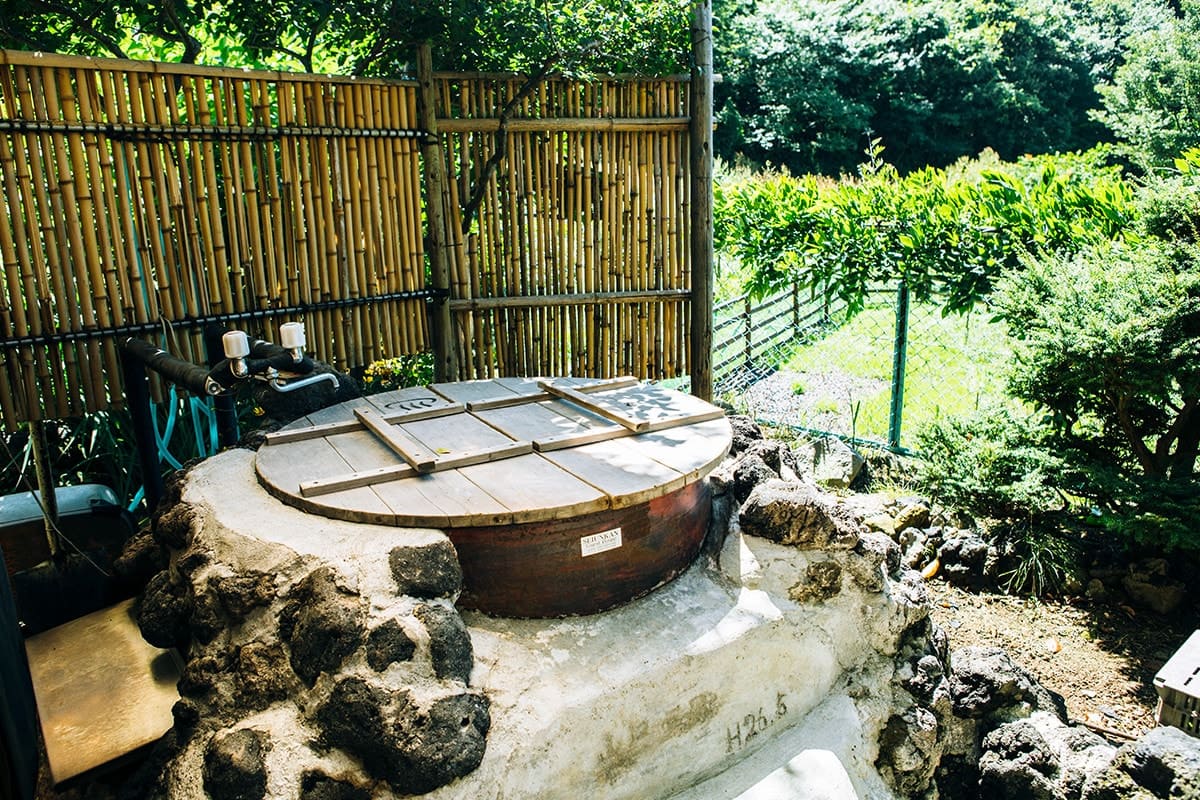 宮坂さん自作の立派な五右衛門風呂。隣には椅子やテーブルが置かれた休憩場所があり、風呂上がりに夜空を眺めながらビールで一服すれば、最高の気分を味わえる。藤棚下の耕作放棄地はDogrun&Gardenとして借用。